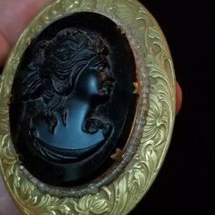 "*Thank you for visiting my shop. Please read the FULL description by clicking on \"Learn more about this item\". All items are Final Sale, no returns.* This is a gorgeous black glass cameo set in a very ornate brass finish metal frame. I date this to somewhere around 1940's or 1950's. The cameo is very 3-dimensional. This is quite a statement piece! It comes on a gold tone 24 inch chain with a clasp. The cameo alone is 36 x 47 mm. The entire piece measures 2 x 2 5/8 inches. The cameo is in exce Vintage Black Jewelry With Antique Finish, Vintage Black Medallion Jewelry, Vintage Black Brass Jewelry, Black Vintage Brass Jewelry, Vintage Black Jewelry For Collectors, Vintage Black Cameo Jewelry, Black Cameo Medallion Jewelry, Black Cameo Jewelry For Collectors, Collectible Black Cameo Jewelry