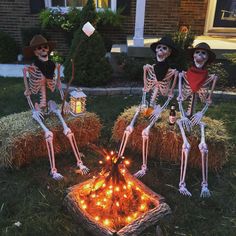 three skeletons sitting on hay bales in front of a house decorated with halloween decorations