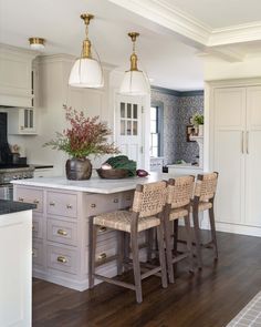 a kitchen island with stools in front of it and lights hanging from the ceiling