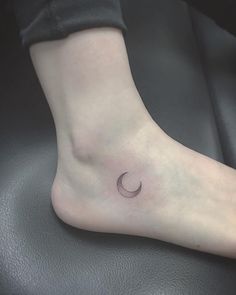 a woman's foot with a small crescent tattoo on the left side of her ankle