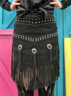 This Scully skirt features genuine leather, studs at the waist and hipline, concho accents along with fringe on the v-shaped hem. This classic western styled skirt will make a fresh, fun addition to any wardrobe. Great paired with your favorite boots! Genuine lamb suede leather Polyester lining Zipper Back V Hemline Studs at the waistband and hipline Concho accents Long fringe accents Approximate waist size: S = 30 ". M = 32". L = 33" XL = 34" Fall Festival Fringe Skirt, Black Western Style Bottoms For Fall, Crochet Lace Skirt, Cowgirl Skirt, Suede Fringe Skirt, Western Skirts, Cowgirl Dresses, Beige Crochet, Western Apparel