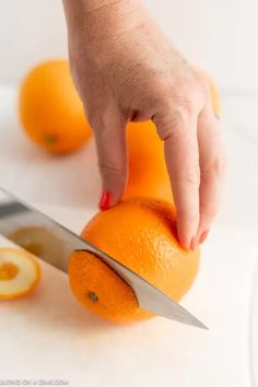 a person cutting an orange with a knife