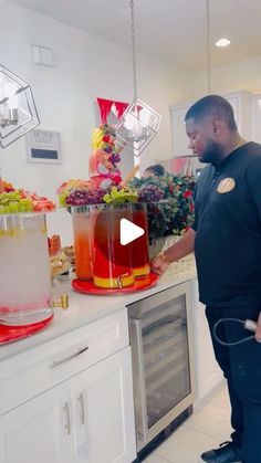 a man standing in front of a counter filled with drinks and fruit on top of it