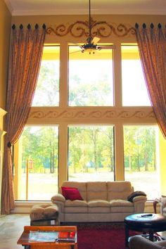 a living room filled with furniture and a large window covered in drapes, next to a fire place