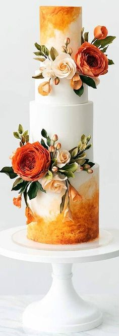 a three tiered cake with orange flowers on top and white frosting around the edges