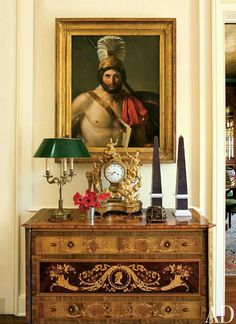 an ornate dresser with a painting on the wall