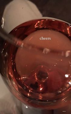 a person holding a wine glass with the word cheers on it