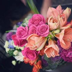 a bouquet of flowers sitting on top of a table in front of a person's hand