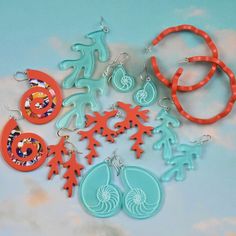 a collection of earrings and earring sets on a blue surface with clouds in the background