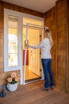 a woman is opening the door to her house with a cat sitting on the porch