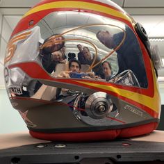 a helmet with many people in it sitting on top of a table next to a laptop computer