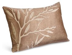 a brown and white pillow with leaves on it's side, in front of a white background