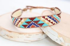 Introducing our adjustable southwestern beaded cuff bracelets! This colorful cuff bracelet is handmade with a southwestern-inspired pattern in cream, dark red, blue, orange, turquoise, and soft yellow.The bracelet is strung on strong beading thread and flexible leather cord with an adjustable closure, making it easy to put on and take off, while also allowing you to customize your fit. It will fit 6-8 inch wrists.Whether you're dressing up for a special occasion or just accenting your everyday s Adjustable Southwestern Blue Cuff Bracelet, Adjustable Beaded Bohemian Cuff Bracelet, Handmade Southwestern Brown Beaded Bracelets, Southwestern Handmade Brown Beaded Bracelets, Handmade Adjustable Southwestern Friendship Bracelets, Southwestern Style Adjustable Cuff Bracelet With Round Beads, Southwestern Cuff Bracelet With Round Beads, Handmade Southwestern Friendship Bracelets, Adjustable Southwestern Friendship Bracelets