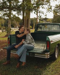 two people sitting on the back of a pickup truck