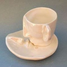 a white cup and saucer on a gray surface