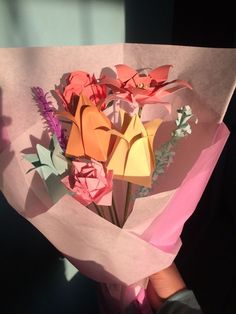 someone is holding a bouquet of origami flowers