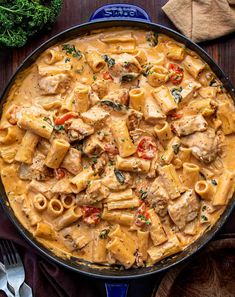 a skillet filled with pasta and chicken in a creamy sauce, garnished with parsley