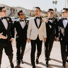 a group of men in tuxedos standing next to each other on a sidewalk