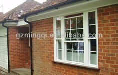 a red brick house with white windows and a black metal pole on the side of it