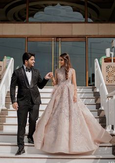 a man and woman in formal wear walking down stairs