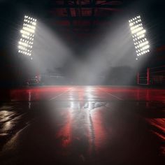 an empty basketball court with lights shining on the floor and in the background are floodlights