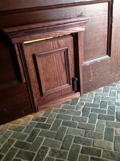 an open wooden door on the side of a brick wall next to a tiled floor