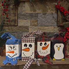 three snowmen and two penguins wrapped in burlocks are sitting on a mantle