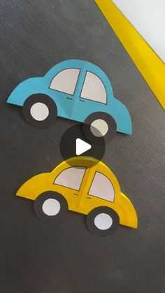 two paper cars are sitting on top of each other, one is blue and the other is yellow