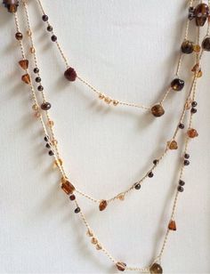 multi strand necklace with various beads and gold chains on a white background, close up