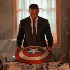 a man in a suit and tie standing over a bed with a captain america shield on it