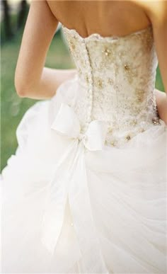 a woman in a white wedding dress with a bow on her waist and the back of her dress