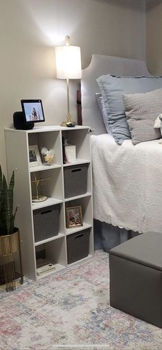 a bedroom with a bed, nightstands and shelves on the floor in front of it