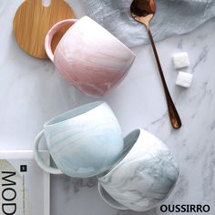 marbled cups and spoons on a white table with wood serving utensils