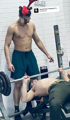 a man with reindeer antlers on his head lifts a barbell while another man squats behind him