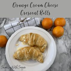 orange cream cheese crescent rolls on a white plate next to some tangerines and a towel