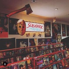 the inside of a movie store with many movies on shelves and posters hanging from the ceiling