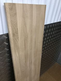 a wooden door sitting next to a black metal flooring mat and a white wall