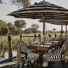 an outdoor dining area with zebra chairs and umbrellas