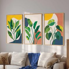 three paintings hang on the wall above a couch