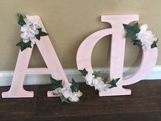 the letters are painted pink and have flowers on each letter, along with greenery