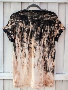 a black and white tie dye shirt hanging on a wooden hanger against a white wall