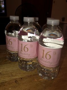 three bottles of water sitting on top of a wooden table