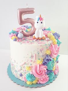 a birthday cake decorated with flowers and a unicorn figurine on the number five