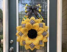 a yellow sunflower wreath is hanging on the front door with a black and white bow