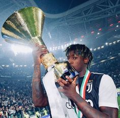 a man holding up a trophy in front of a crowd at a soccer game,