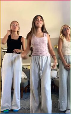 three girls standing in front of a mirror with their hands on their hipss and looking up