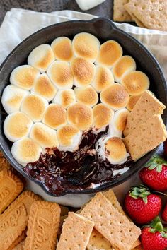 a skillet filled with marshmallows, chocolate sauce and graham crackers