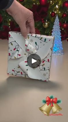 a person opening a christmas present in front of a christmas tree