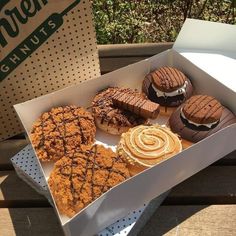 a box filled with assorted pastries sitting on top of a wooden table