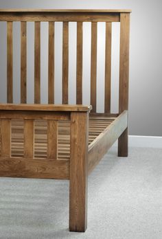 a wooden bed frame with slatted headboard and foot board on carpeted flooring